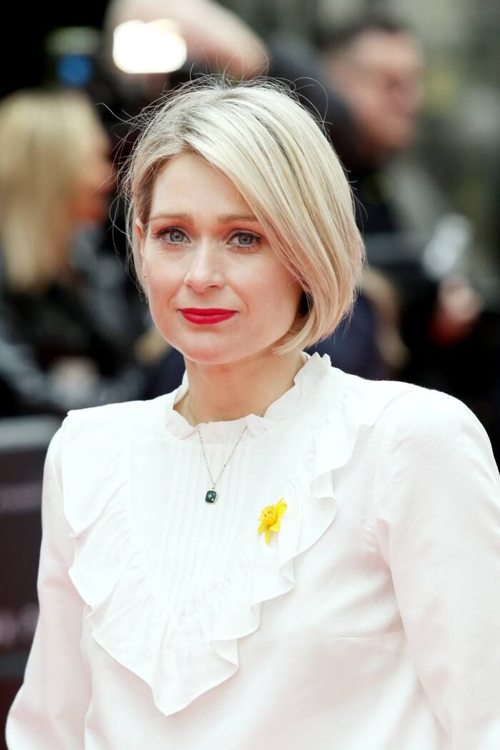 a woman with blonde hair wearing a white blouse and red lipstick is smiling at the camera