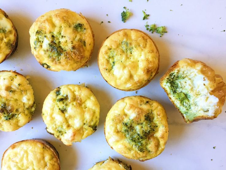 there are many small muffins on the counter top, some with cheese and broccoli