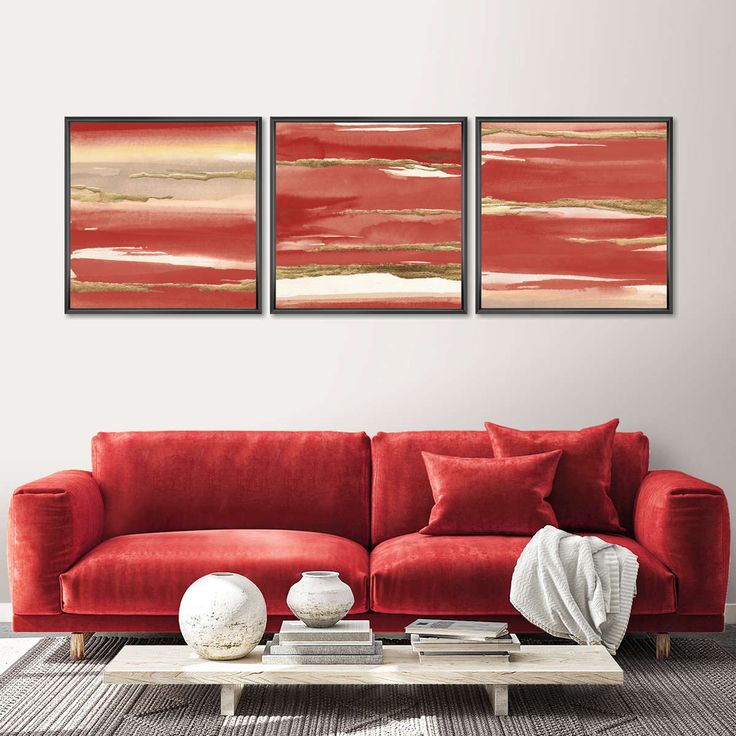 a living room with red couches and two paintings on the wall above them,