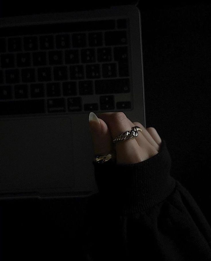 a person is holding their hand up in front of a laptop computer with the light on