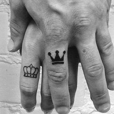 two fingers with crowns tattooed on them, one has a crown and the other has a heart