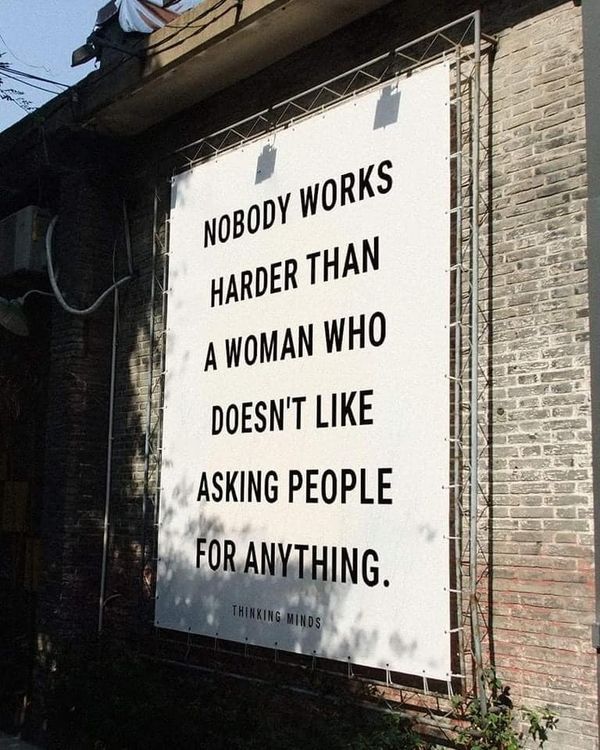 a sign on the side of a building that says nobody works harder than a woman who doesn't like asking people for anything