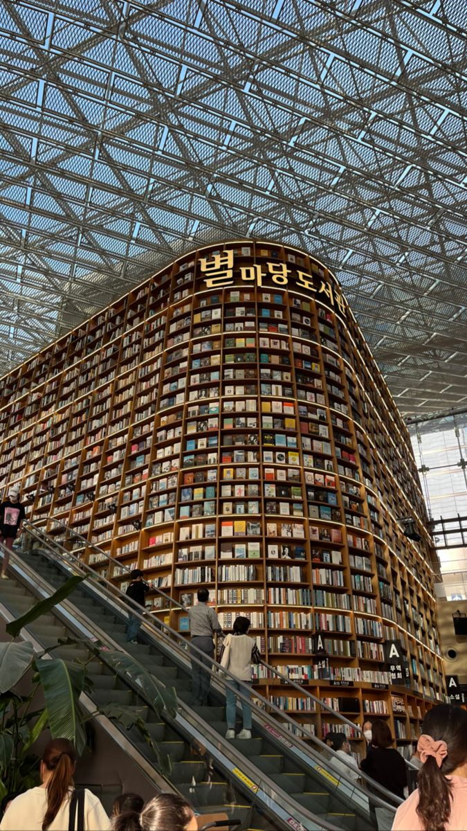 people are walking up and down an escalator in a building with many books on it