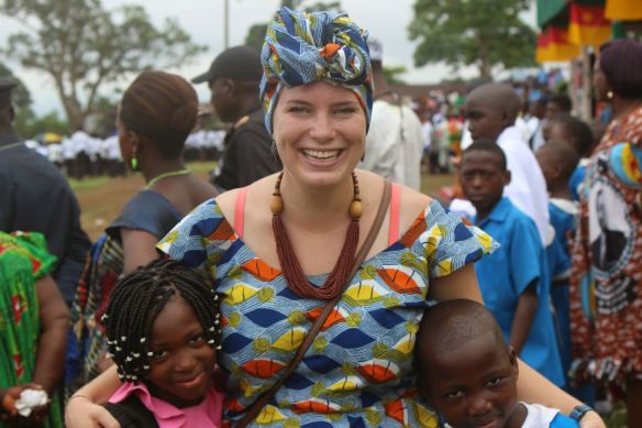 a woman standing next to two small children in front of a group of other people