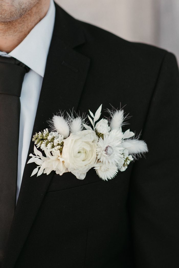 a man wearing a suit and tie with flowers on it's lapel pin