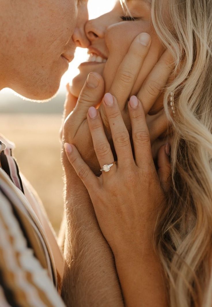 a man and woman holding each other close to their face with the sun behind them