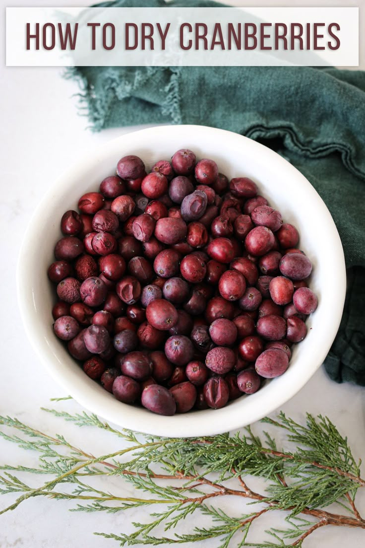 a white bowl filled with cranberries on top of a table next to a green napkin