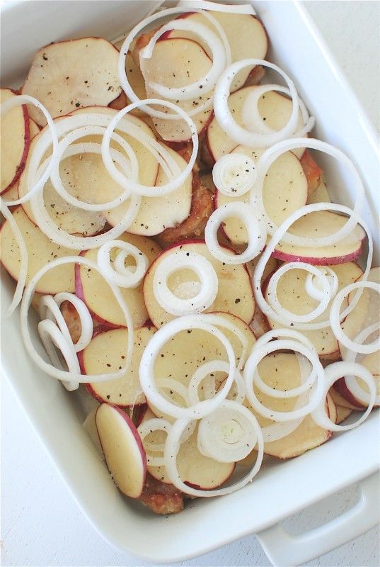 an apple and onion casserole in a white dish with onions on the side