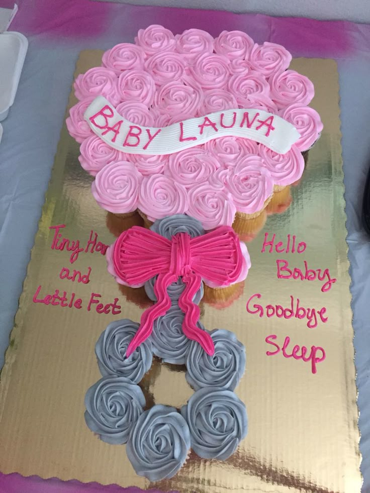 a baby shower cupcake with pink and blue icing is on top of a sheet cake