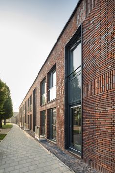 a brick building with several windows on the side and cobblestone walkway between it