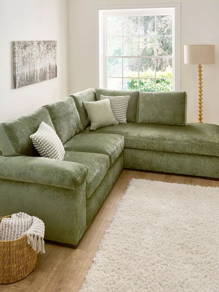 a living room with a large green couch and white rugs on the wooden floor