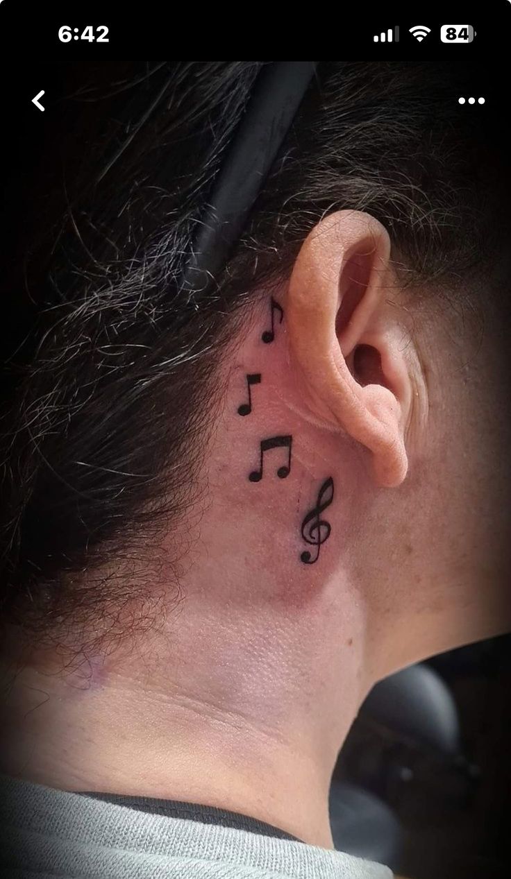 a woman's ear with musical notes tattooed on the side of her neck and behind her ear