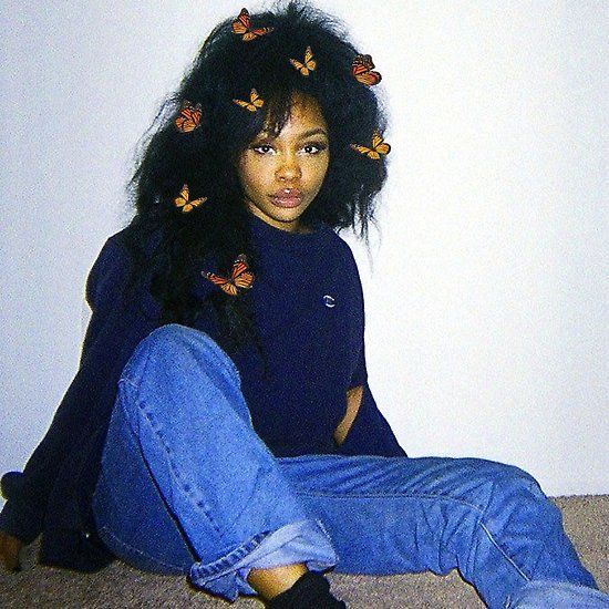 a woman sitting on the floor with her legs crossed and butterflies pinned to her hair