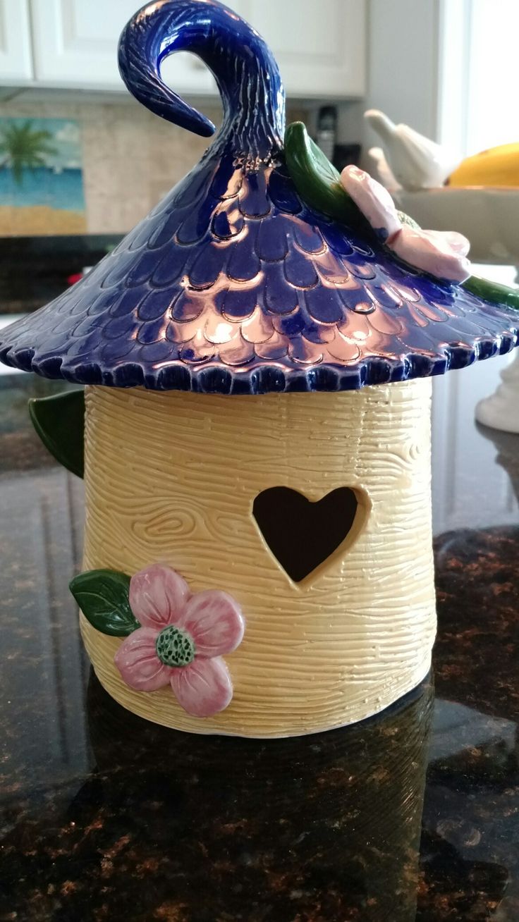 a ceramic birdhouse with a blue roof and pink flowers on it's side