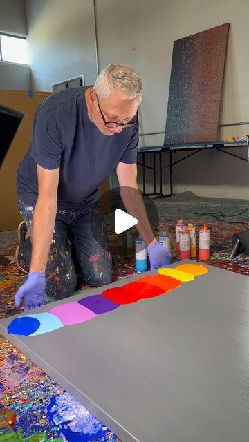 an older man is painting on the floor in his art studio with color swatches