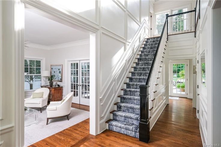 a staircase leading to the upper level of a house with white walls and wood floors