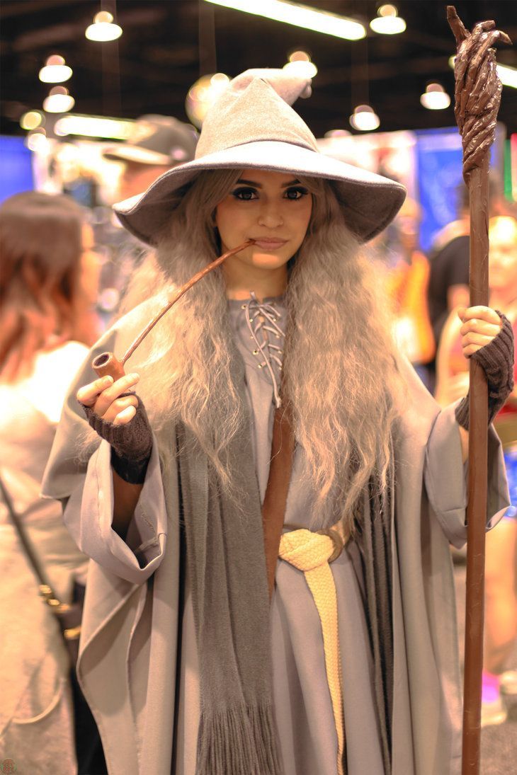 a woman dressed in costume holding a stick and wearing a hat with long white hair