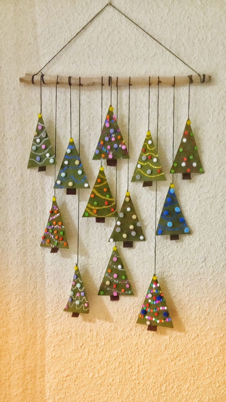 a group of small christmas trees hanging from a wooden frame on a wall next to a white wall