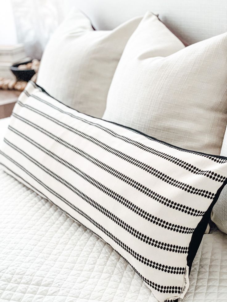 a white bed with black and white pillows