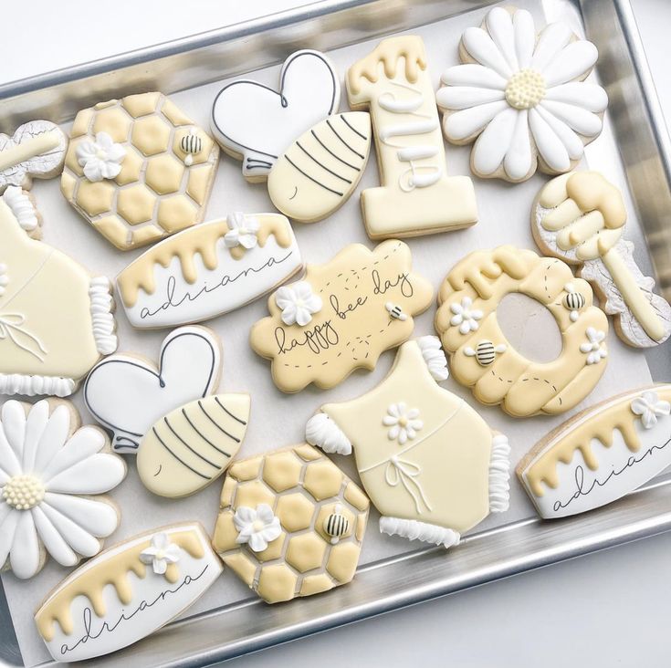 decorated cookies in the shape of flowers and bees on a cookie sheet with congratulations written