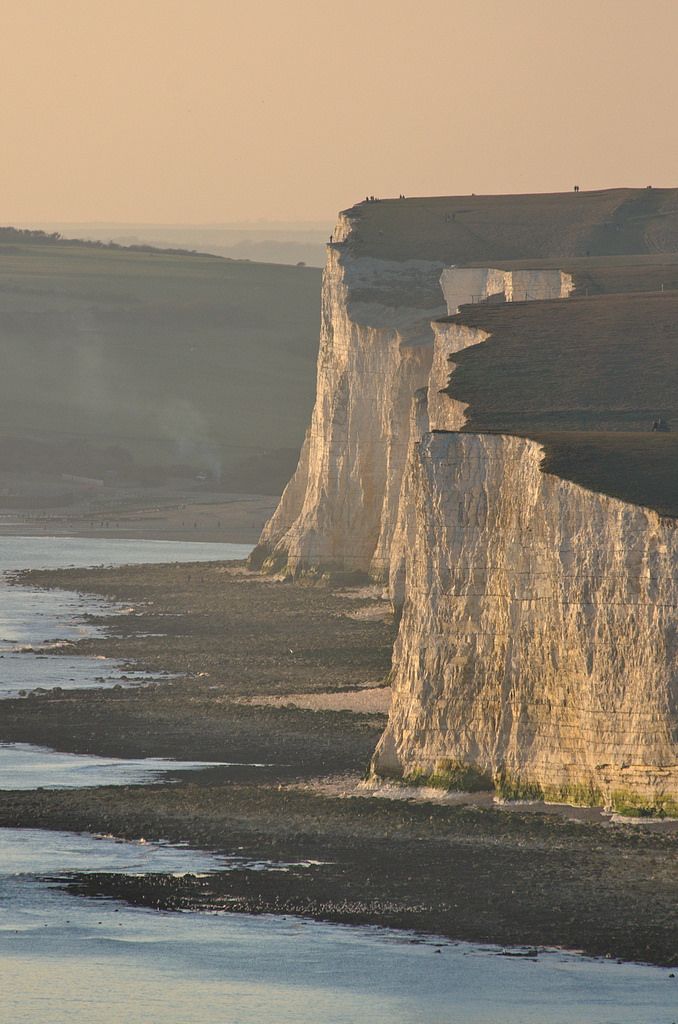 there is a boat that is sitting on the water next to some white cliffs