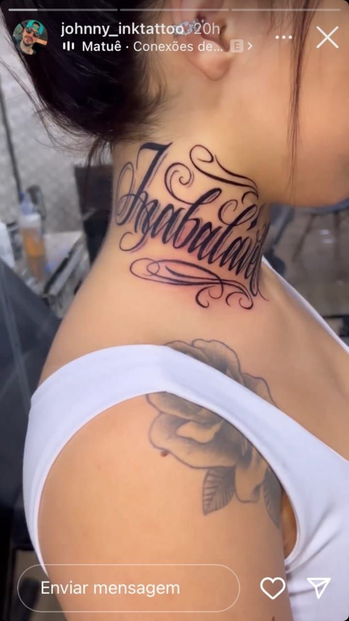 the back of a woman's neck with an inscription tattoo on her left side