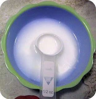 a blue and green bowl with a spoon in the middle, on top of a rock