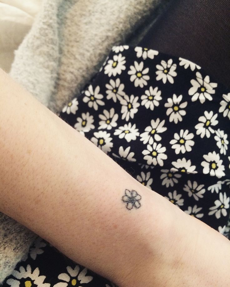 a person with a small flower tattoo on their arm