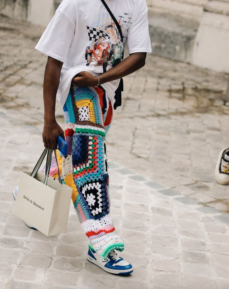 a man is walking down the street with his shopping bag and crocheted pants