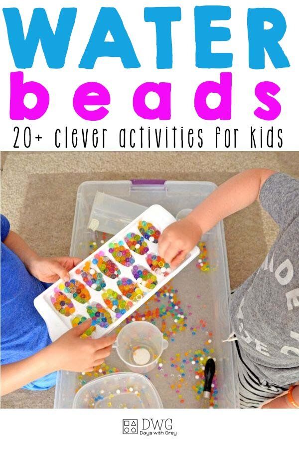 two children are playing with water beads on the floor and in front of a plastic container