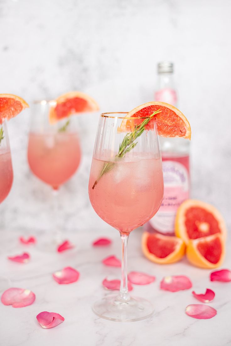 three wine glasses filled with pink grapefruit and garnish