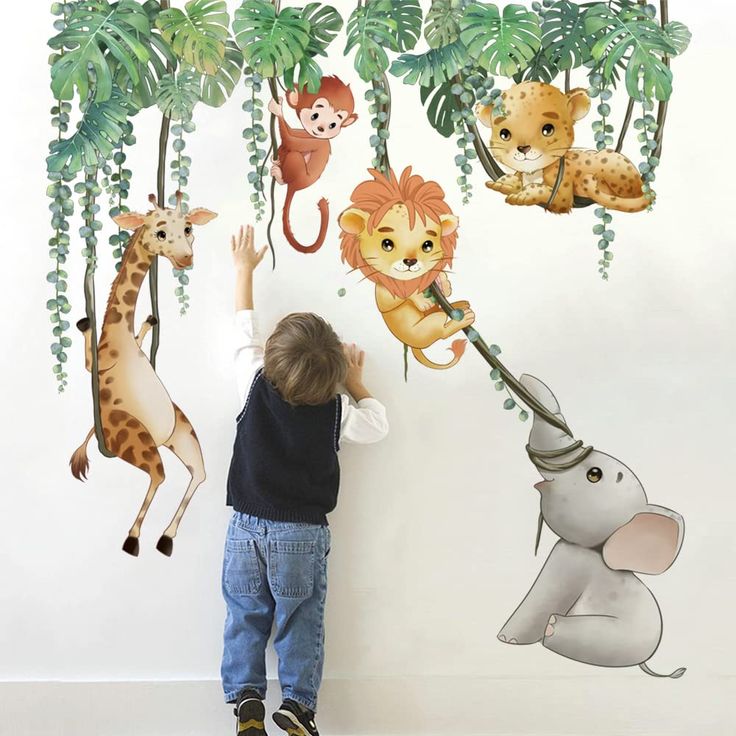 a little boy standing in front of a wall with jungle animals and giraffes on it