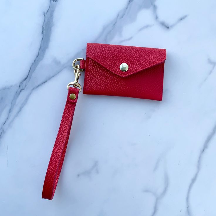 a red wallet with a keychain attached to it on a marble counter top