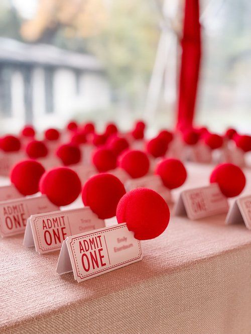 red pom - poms are placed on the table for guests to sit at