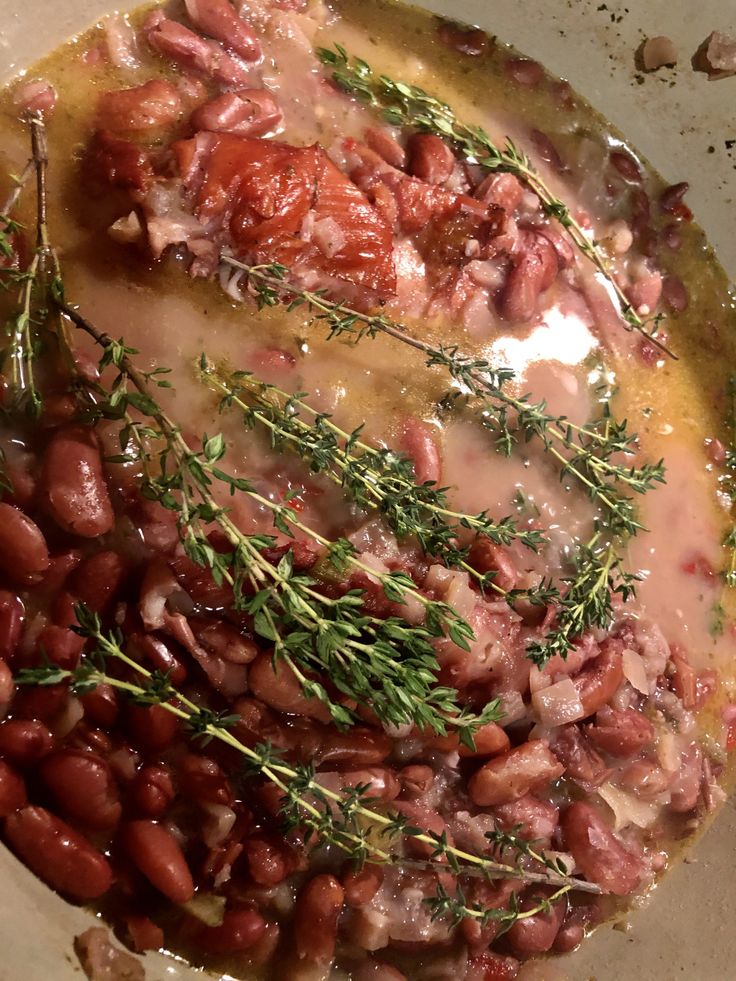 beans, tomatoes and herbs are cooking in a pan