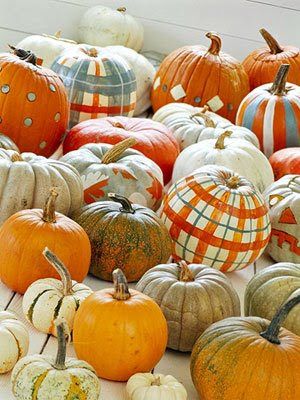 many pumpkins are arranged in rows on the floor and one is painted with an orange, white, and blue checkerboard pattern