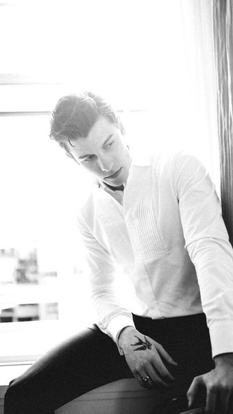 a man sitting on top of a window sill wearing a white shirt and black pants