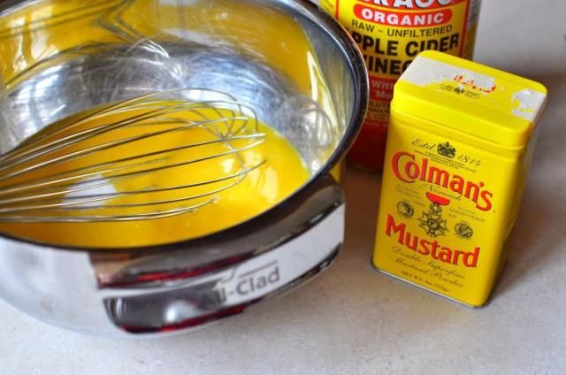 a bowl with whisk and mustard next to other ingredients on a counter top