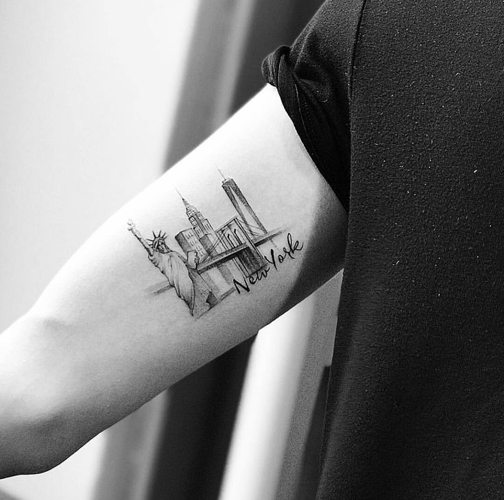 a black and white photo of a person's arm with a city skyline tattoo on it