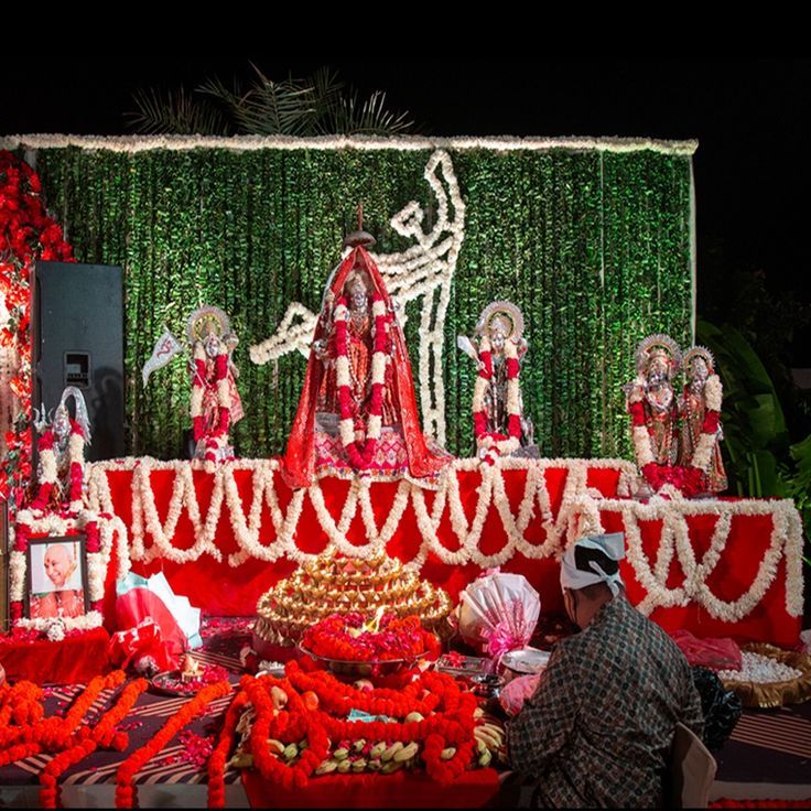 a man sitting in front of a decorated stage with flowers and decorations on the ground