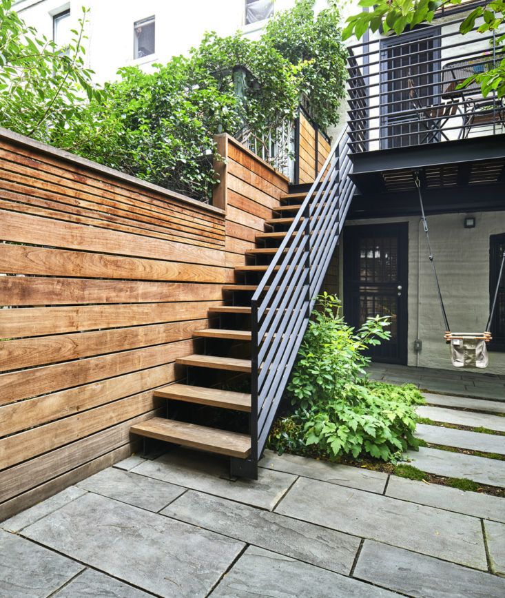 an outdoor stair case with wooden steps and plants on either side, in front of a house