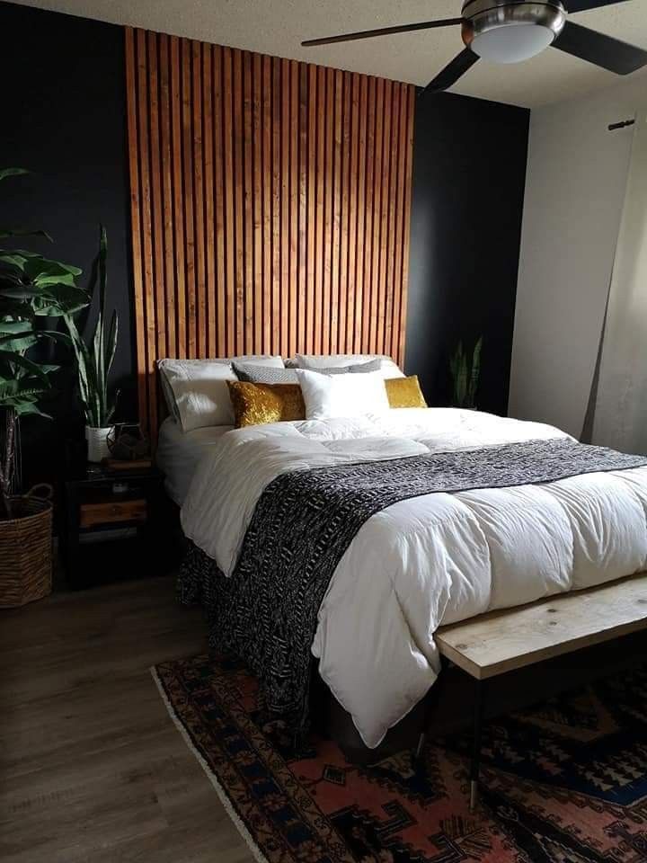 a bed with white sheets and pillows in a bedroom next to a wooden headboard