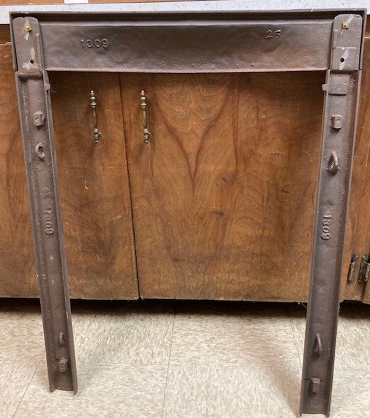 an old wooden cabinet with metal handles and two bars on the bottom, in front of it