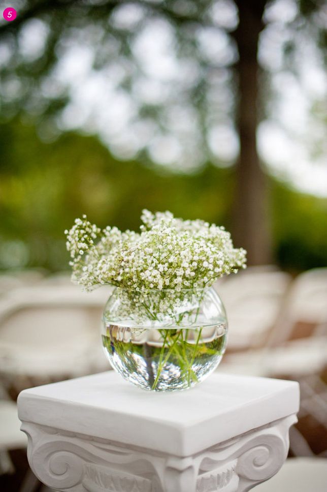 a vase filled with white flowers sitting on top of a table next to an empty chair