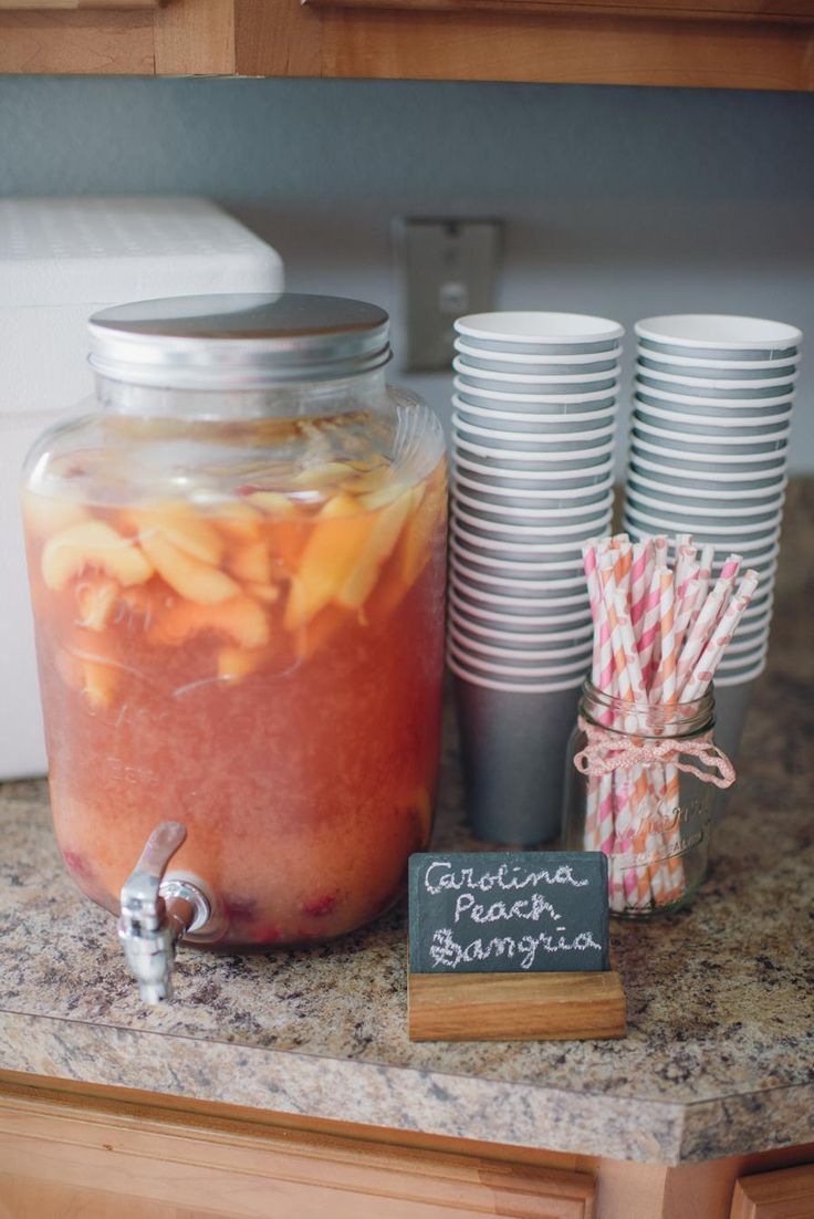 a jar filled with liquid next to cups and paper straws on top of a counter