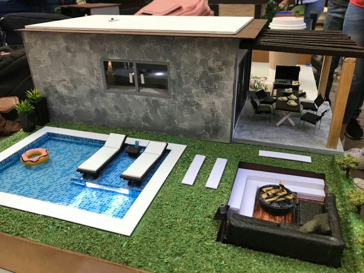 a model house with a swimming pool in the middle and people standing around looking at it