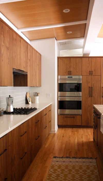 a kitchen with wooden cabinets and white counter tops, along with a rug on the floor