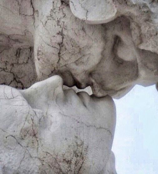 an artistic black and white photo of two people kissing in front of a rock formation