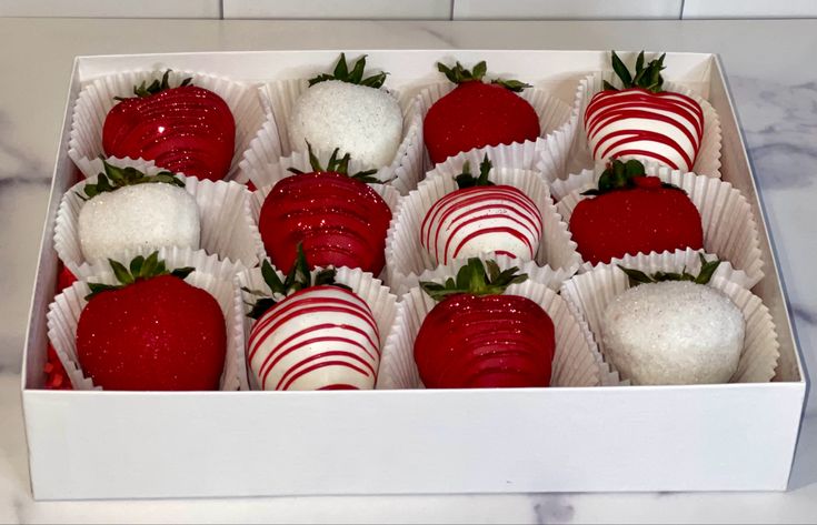 a box full of chocolate covered strawberries on top of a marble countertop with white and red decorations