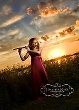 a woman in a red dress is holding a flute and posing for the camera at sunset